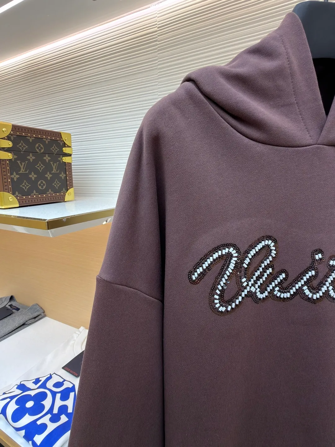 LOUIS VUITTON beaded embroidered letter hooded sweatshirt ●Item number: 1682118-A60 ●Material: pure cotton fish scale base fabric ●Technology: Pearl embroidery production ●Color: brown ●Version: fitted version ●Weight: about 830 grams ●Size: S-M-L-XL ●Description: The fabric is made of 26S double yarn + 10S fish scale bottom brushed fabric, weight 380g, with 21S double yarn 2*2 rib, weight 380g. This kind of fabric is treated with fleece to form a layer of soft and plump fluff on the inside; the improved fish scale knitting method forms a delicate concave and convex texture on the bottom surface, similar to the arrangement of fish scales. Effectively increases the air storage layer and improves thermal insulation performance. The front of the fabric is smooth and smooth, while the back is soft and waxy. It has excellent moisture absorption, breathability, wrinkle resistance and drape, and is thicker and crisper than ordinary sweatshirt materials. It gives clothes excellent warmth retention, breathability and skin-friendly touch. The Vuitton script on the chest is embroidered with beads. During the embroidery process, tiny beads are fixed on the fabric together with embroidery thread. The direct characteristics brought by this process are a strong three-dimensional sense, a unique sense of weight and a reflective effect that changes with the light. The overall wiring is straight and delicate, the fabric is comfortable and soft, and the color is consistent without color difference. It can be matched with the same style to create a fashionable look and control various occasions. Customized accessories, complete with three standards, same style for men and women!